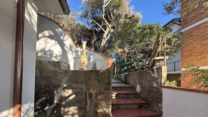 A narrow stairway with red steps leading up to a stone wall, a sign with 'GIA' visible, and trees in the background.
