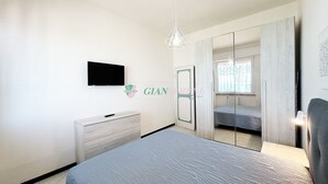 A bedroom with a bed, a dresser, a TV, a wardrobe, and a mirror.
