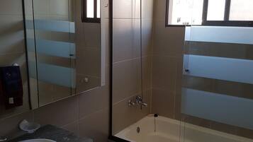 Een douche, handdoeken, zeep, toiletpapier