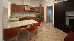 A compact kitchen with a dining table and chairs, a stove, oven, and a black TV stand.