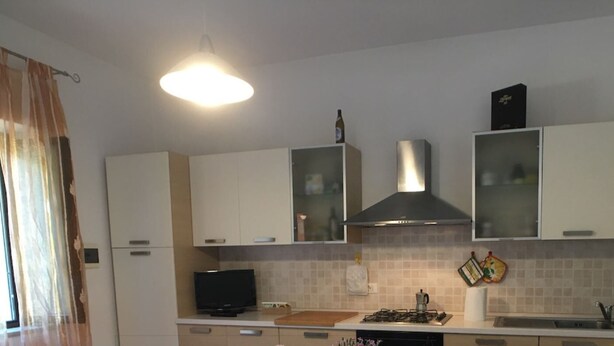 A kitchen with white cabinets, a gas stove, a sink, and a television. - 5 BEDS, in front of Bagno Paradisino (San Vincenzo)