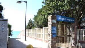 Een stenen poort met een blauw bordje voor Baque Santa Caterina, een bar, en uitzicht op zee.