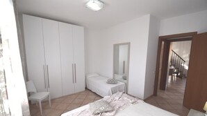 Een slaapkamer met een bed, een stoel, een kledingkast en een spiegel.