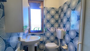 A bathroom with a sink, toilet, and bidet, featuring blue patterned tiles and a window. - THREE-ROOM APARTMENT SLEEPS 5 IN THE CONCHIGLIA (San Vincenzo)