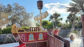 Une structure de jeu sur le thème d’un bateau de pirates, avec un toboggan, une échelle de corde et un tonneau.