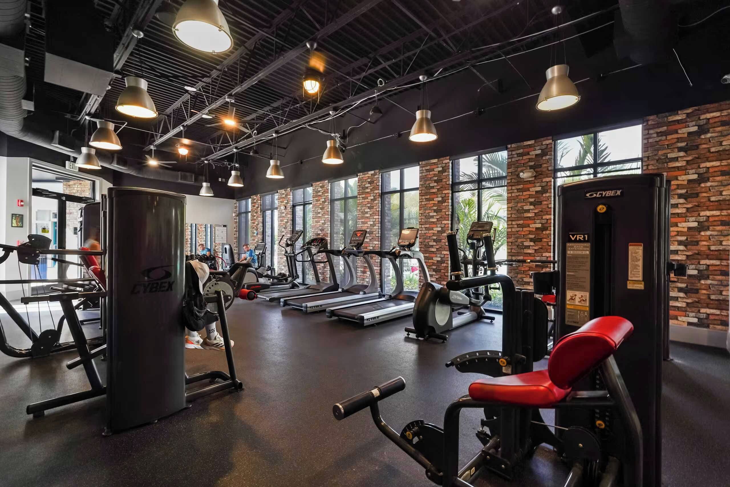 A gym with treadmills, weight machines, and a red bench.