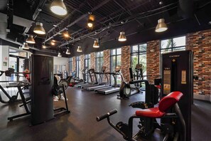 A gym with treadmills, weight machines, and a red bench.