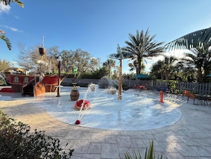 A water play area with a pirate ship, palm trees, and a wooden fence. - Escape to a 4BR Villa w/ Arcade, Pool & Mini Golf (Davenport)