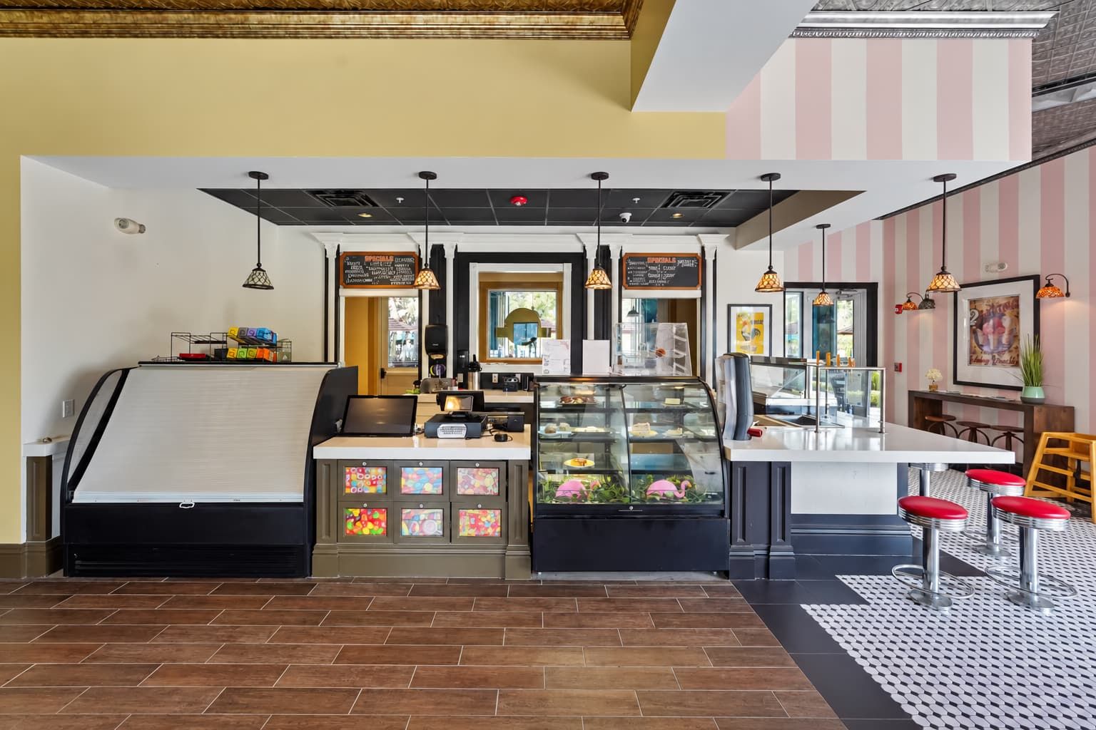 A restaurant with a counter, a display case with food, and a seating area with stools.
