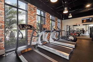 A gym with treadmills, a brick wall, and large windows. - Escape to a 4BR Villa w/ Arcade, Pool & Mini Golf (Davenport)