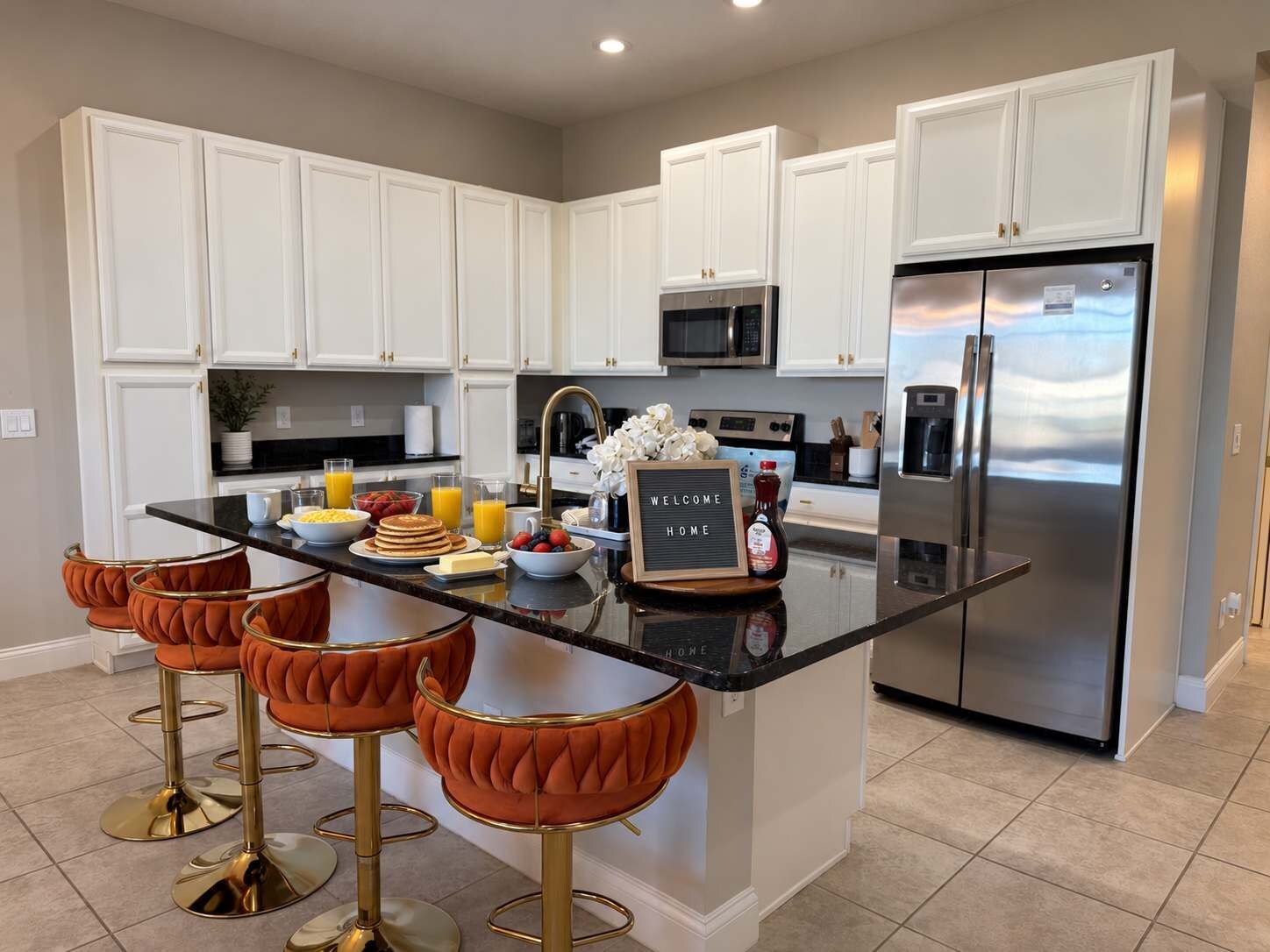 A modern kitchen with white cabinets, stainless steel appliances, and a central island with stools.