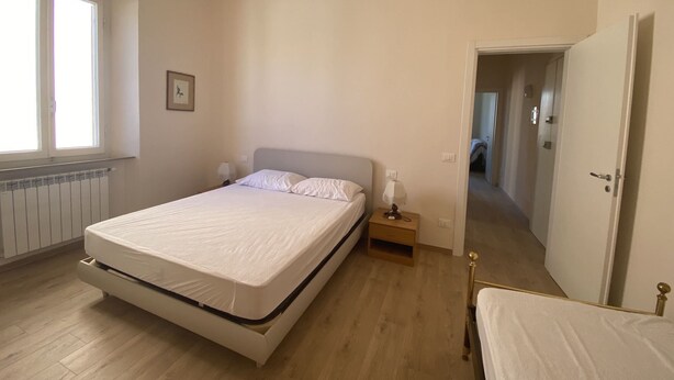 A bedroom with a bed, bedside table, and a window.