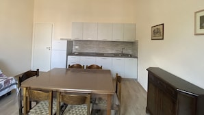 A compact kitchen with white cabinets, a tiled backsplash, and a dining area with a wooden table and chairs.