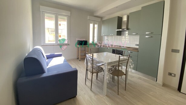 Eine moderne Küche mit Esstisch und Stühlen, einem Sofa und einem Fenster mit Jalousien.