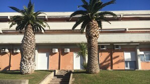 A building with a staircase leading to a second floor, flanked by palm trees. - TWO-ROOM APARTMENT SLEEPS 4 IN THE LA PIANA AREA (San Vincenzo)