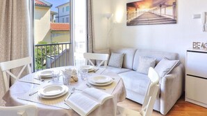 A dining area with a table set for four, a sofa, and a refrigerator.