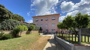 A pink building with a paved pathway leading to a gated entrance. - 5 beds with garden and air conditioning (San Vincenzo)