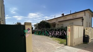 A gated entrance to a property with a paved driveway leading to a building.