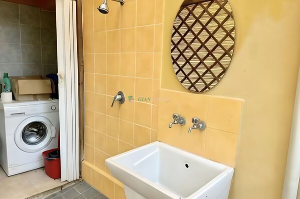 Un baño con lavadora, lavamanos y ducha.