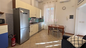 Una cocina compacta con refrigerador, estufa y comedor.
