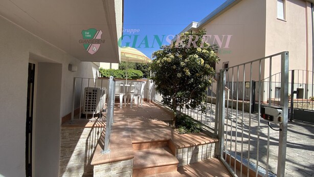 Une propriété résidentielle dotée d’un escalier en pierre menant à un balcon, d’une porte en métal et surplombée d’un ciel bleu dégagé.