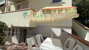 Un balcon avec une table et des chaises, un parasol et un bâtiment orné d’un logo.