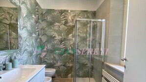 A bathroom with a shower, toilet, and sink. - Seafront building with private parking space (San Vincenzo)