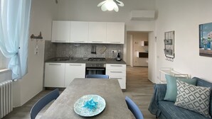 A compact kitchen with white cabinets, a gas stove, and a modern pendant light. - 5 bed places with parking space - ROSS2S (San Vincenzo)