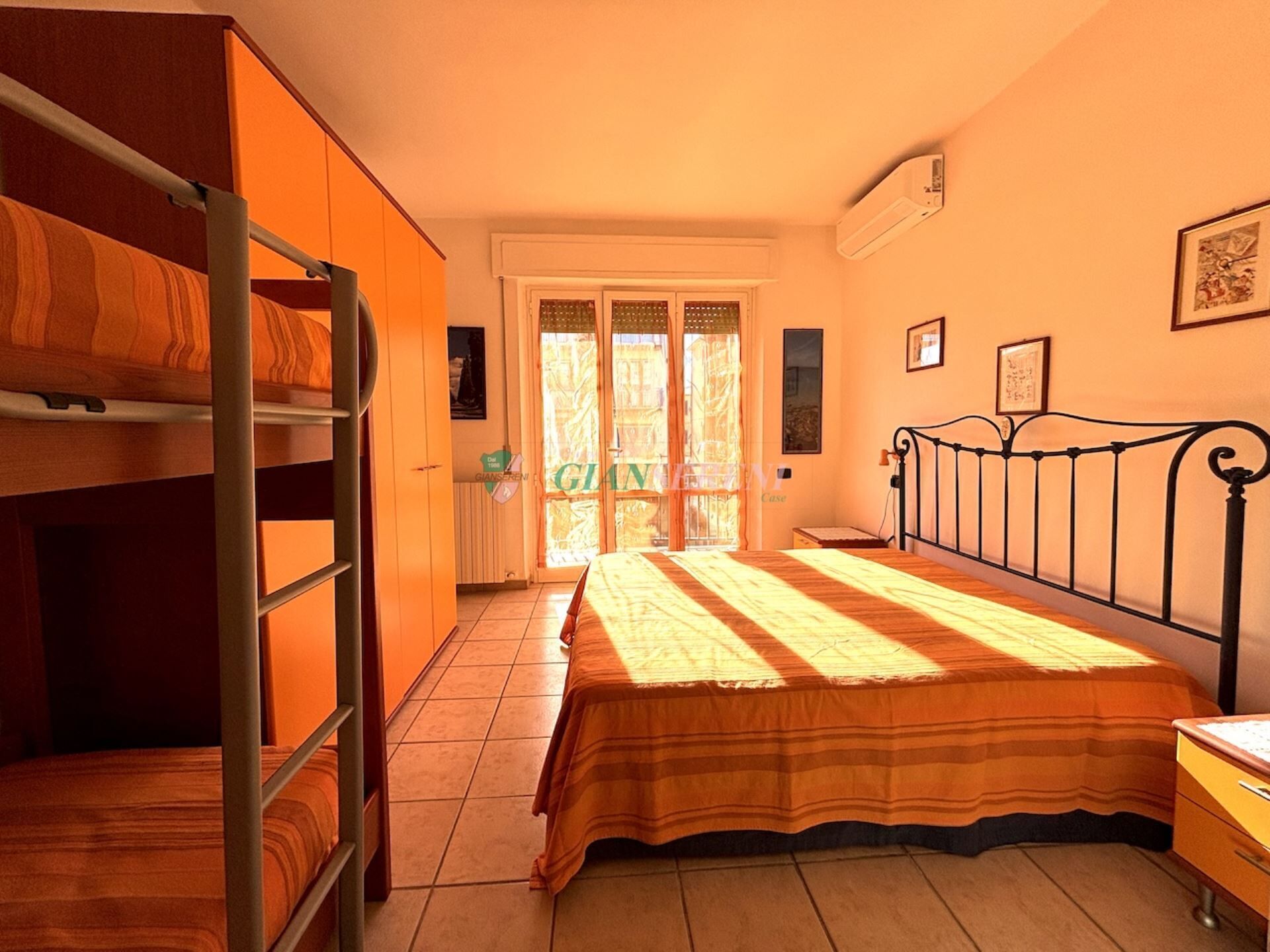 A bedroom with bunk beds, a bed, a dresser, and a window with a view.