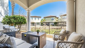 Eine Terrasse mit Gartenmöbeln, einem Grill und Blick auf benachbarte Häuser.