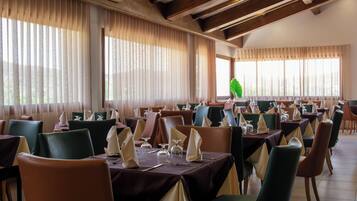 Een restaurant met meerdere tafels gedekt voor diners, met diverse stoelkleuren en tafeldecoraties.