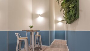 Eine Ecke mit zwei weißen Barhocker, einem kleinen Tisch mit einer Pflanze und Wandleuchten.