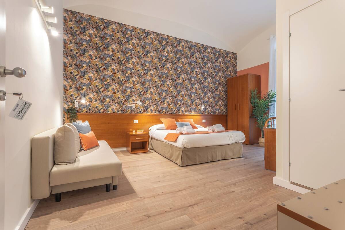 A modern hotel room with a large bed, a sofa, and a wooden headboard.