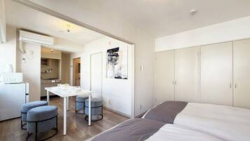 A modern hotel room with a bed, a desk, and a kitchenette.