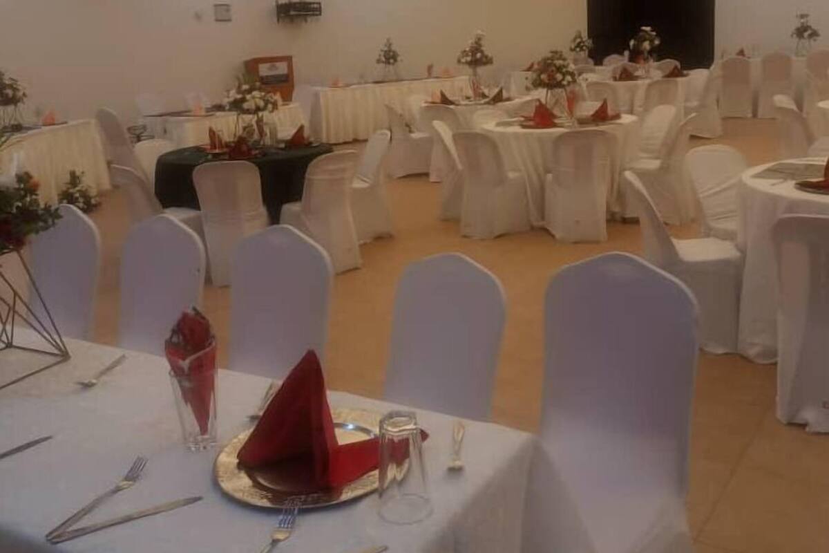 A banquet hall with round tables covered in white tablecloths, white chairs, and floral centerpieces.