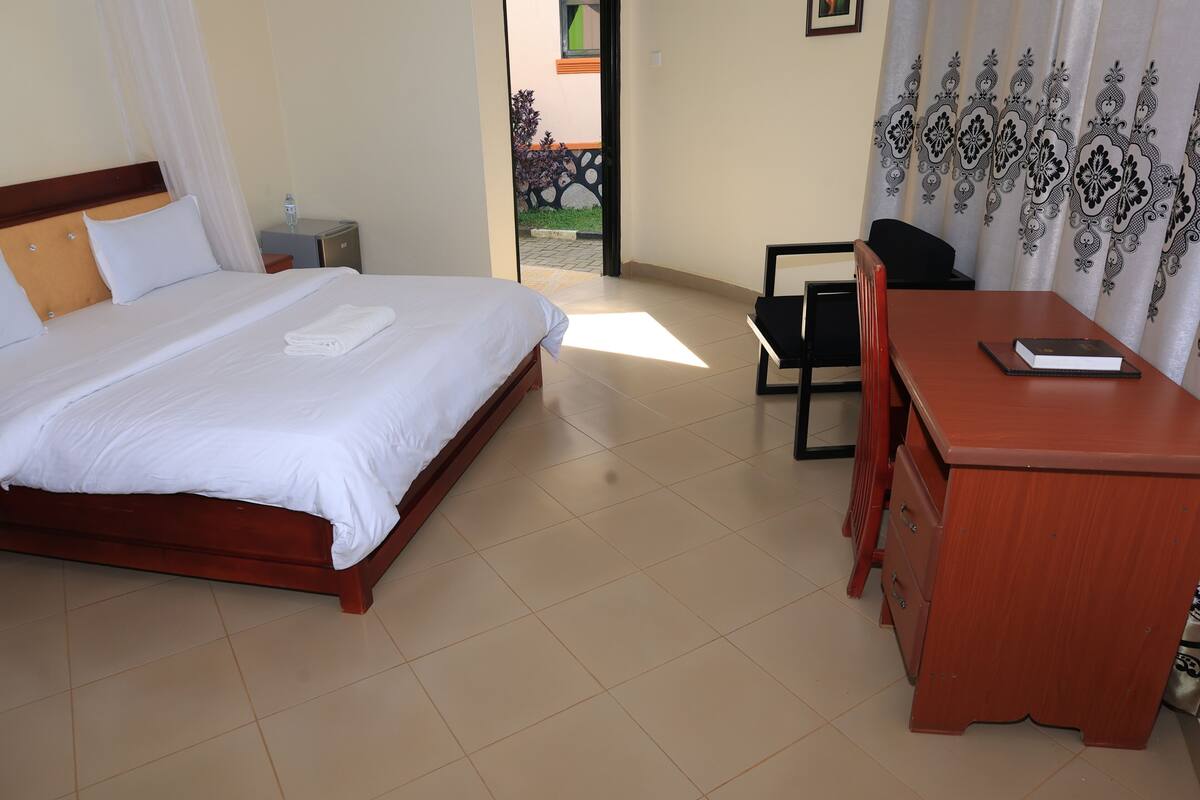 A hotel room with a bed, a desk, a chair, and a view of the outside.