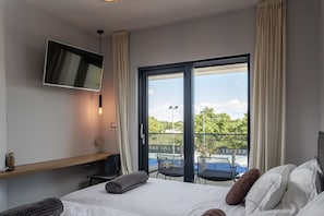 Una camera d'hotel con un letto, una TV fissata al muro, una scrivania con una sedia e un balcone con posti a sedere.