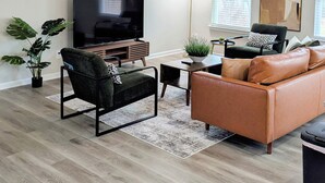Ein modernes Wohnzimmer mit Flachbildfernseher, Ledersofa und Deckenventilator.