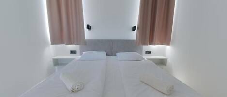 A double bed with white linens, two bedside tables, and a headboard.