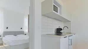 Een moderne hotelkamer met een bed, een kitchenette en een kleine badkamer.