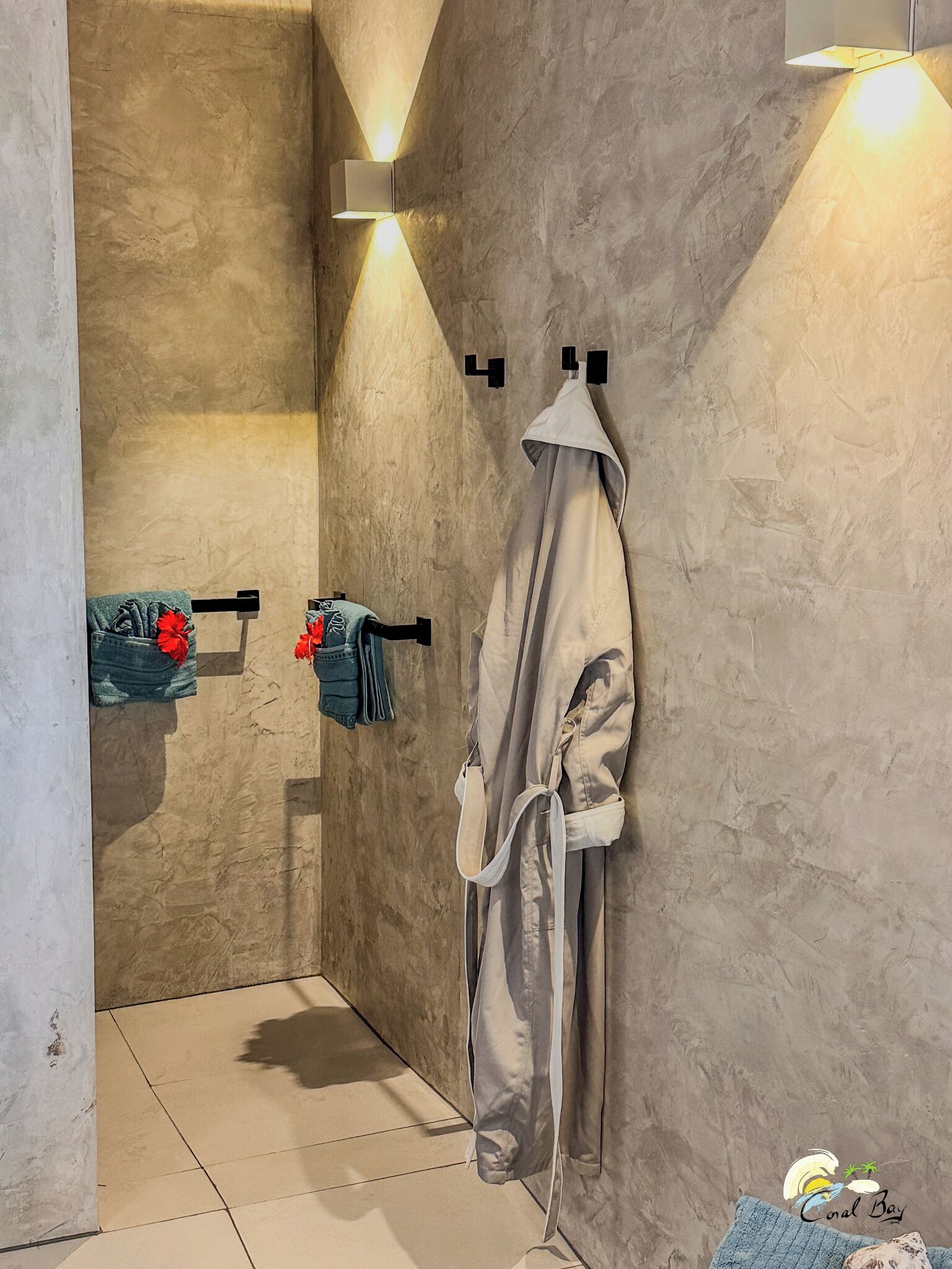 Un bagno moderno con doccia, asciugamani e un accappatoio appeso a un gancio.
