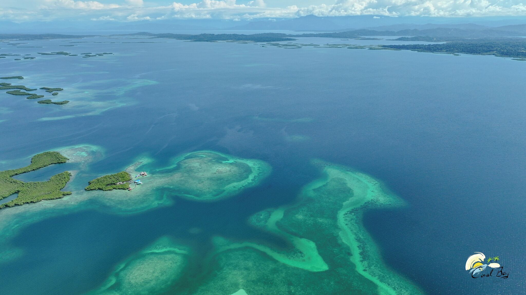 An aerial view of a coastal area with multiple small islands and clear blue waters.
