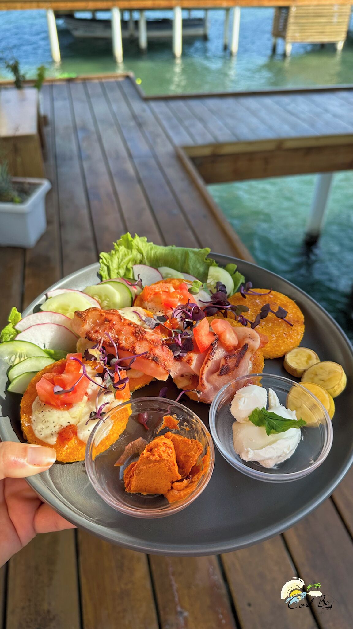 Una bandeja de comida sobre una terraza de madera con vistas al agua.