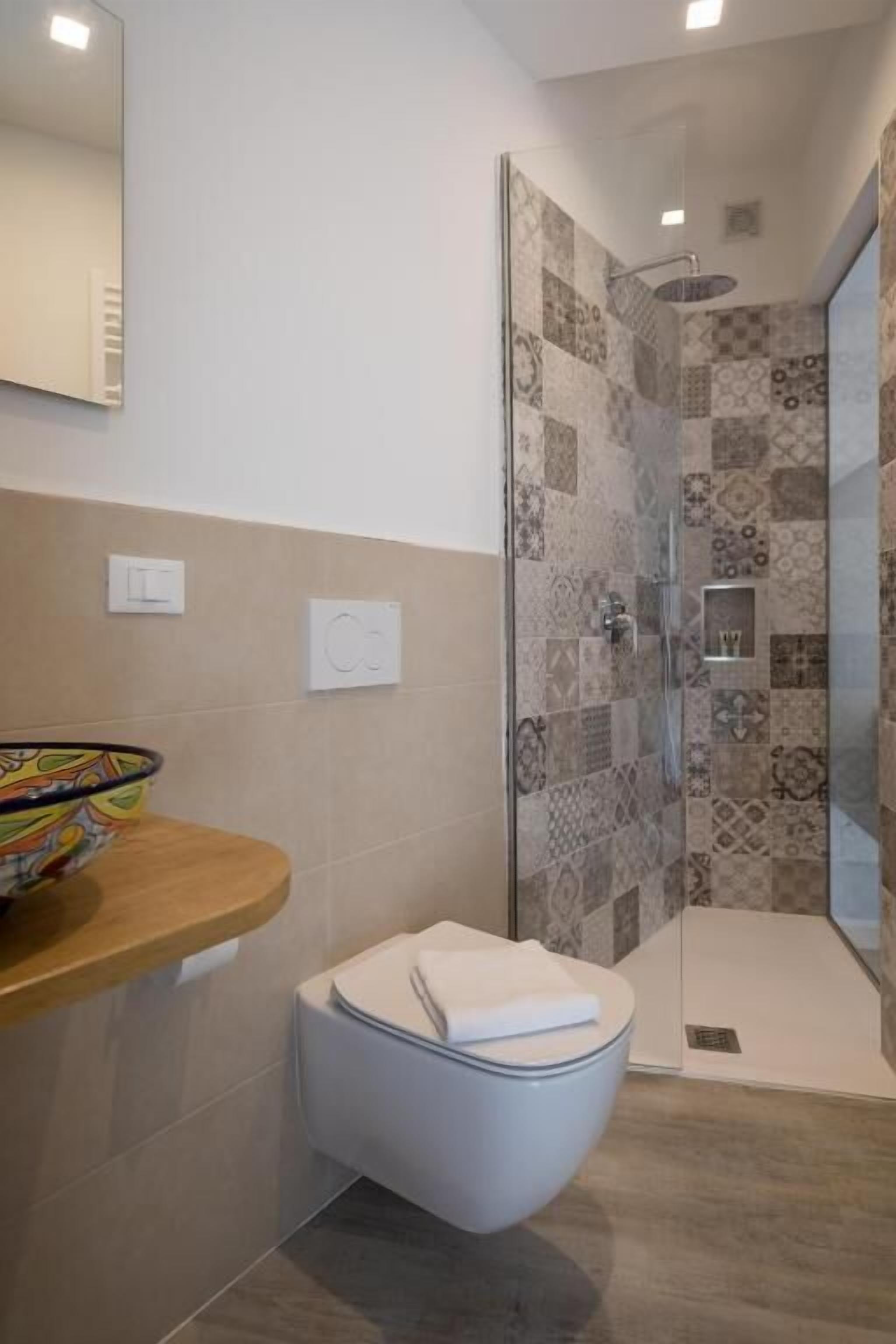 A modern bathroom with a shower, toilet, and a bowl sink.