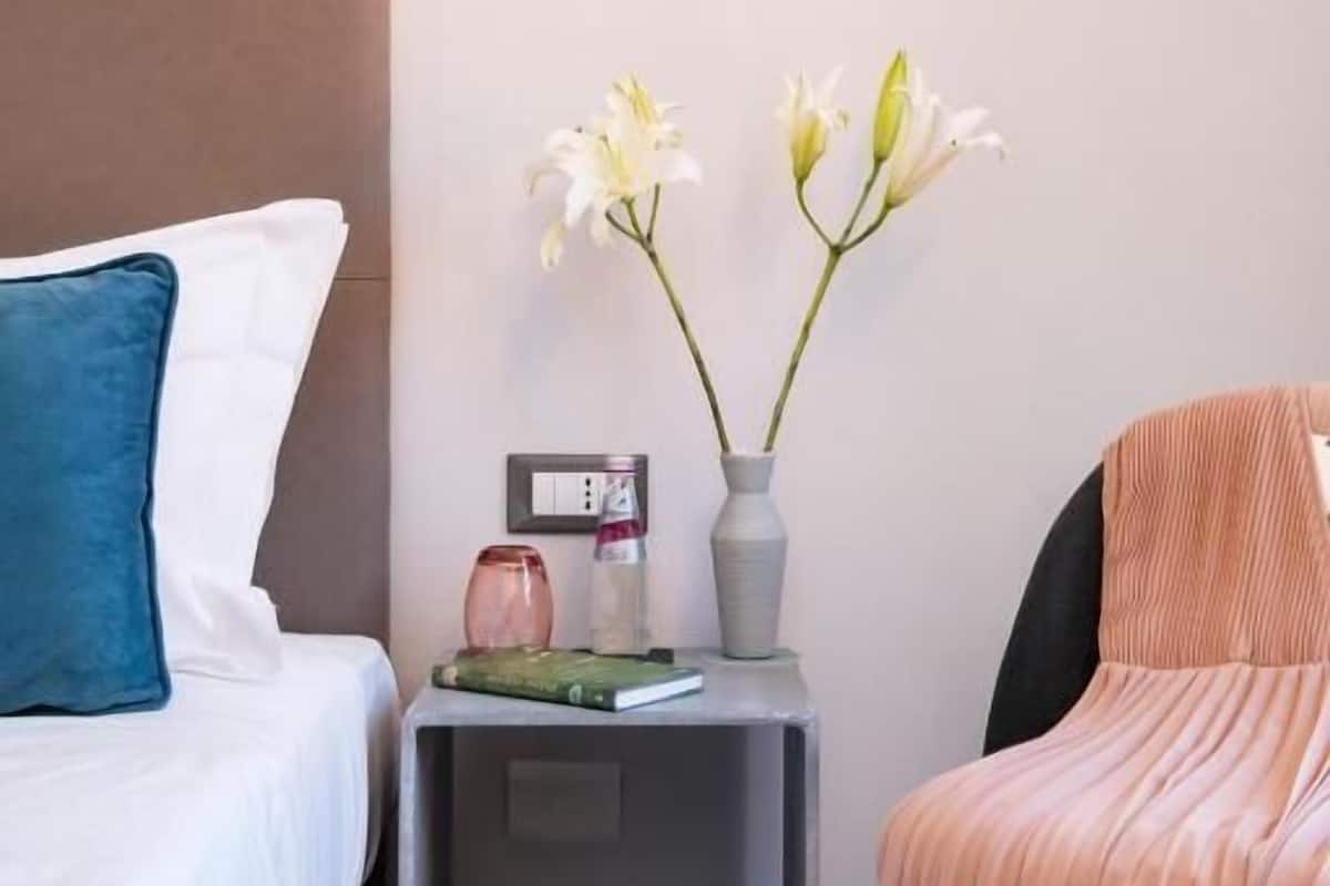 A neatly arranged bedroom with a bed, bedside table, and a chair.