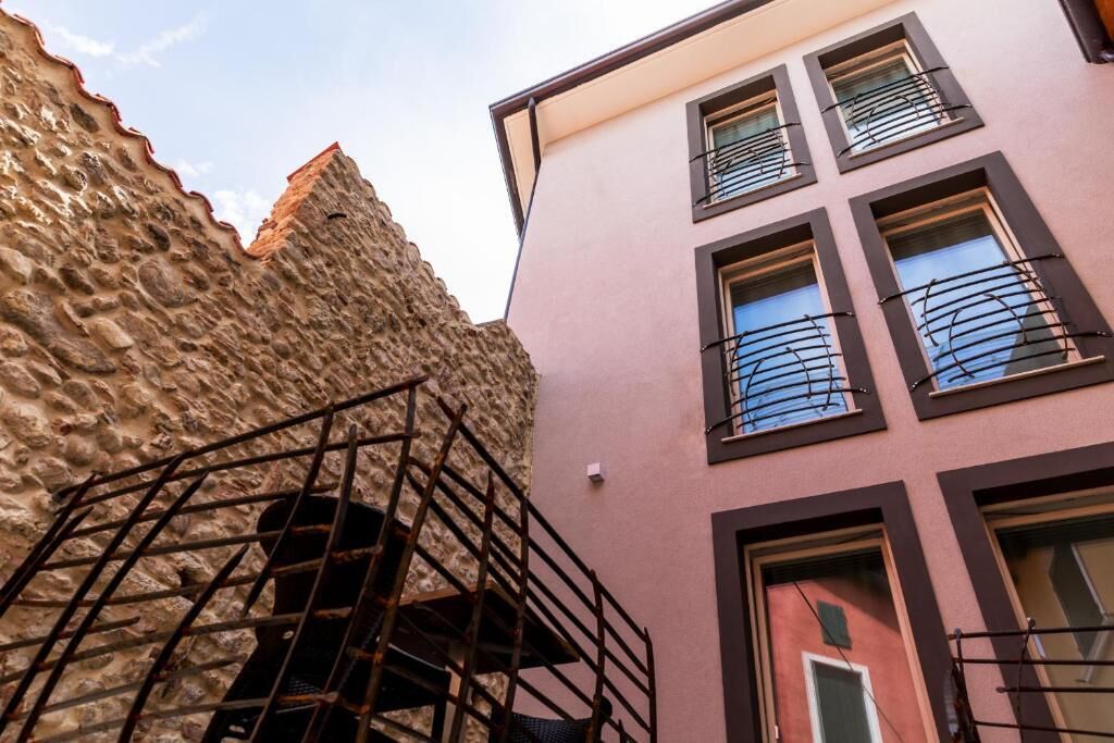 Un bâtiment doté d’une façade en pierre et d’une partie supérieure de couleur rose.
