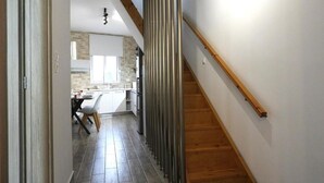 Una cocina moderna con una isla central, escalera de madera y vista al comedor.