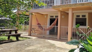 Un edificio a due piani con un balcone, un'amaca e un tavolo da picnic.