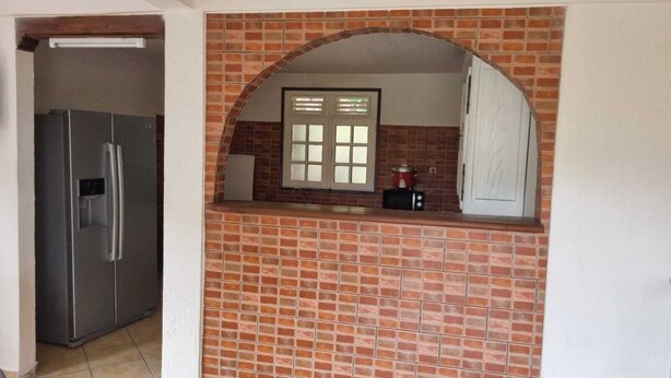 Una cucina con parete rivestita in mattoni, una finestra e un frigorifero.