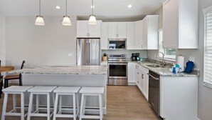 A modern kitchen with white cabinetry, stainless steel appliances, and a marble countertop. - ☀️ Private Pool - Short Walk to Beach - Betty's Beach House ☀️ (Fort Myers Beach)